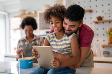 Mutlu Afro-Amerikan ailesi evde aletle eğleniyor. Siyah ebeveynler ve çocuklar dijital tablet kullanıyorlar
