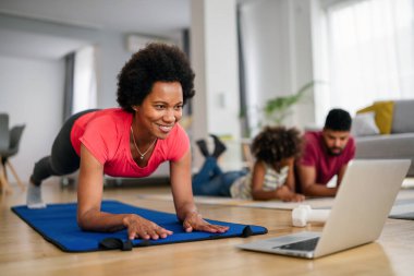 Spor yoga videoları. Evde spor yapma dersi online olarak canlı yayınlanıyor. Mutlu Afro-Amerikan kadın egzersizleri.