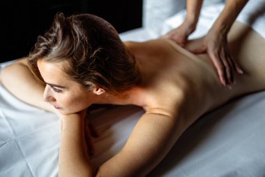 Mutlu profesyonel kadın masajcı masaj masasında masaj yapan, masaj masasında rahat genç bayan bir müşteriye masaj yapıyor.