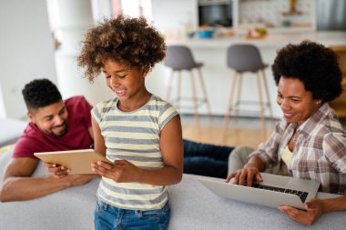 Teknolojik cihazlara takıntılı mutlu Afro-Amerikan genç ailesi dijital tablet, bilgisayar, akıllı telefonlar kullanıyor..