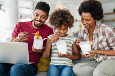 Family home delivary takeaway food concept. Happy african american family eating at living room and enjoying time together. clipart