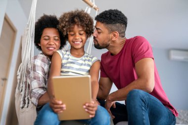 Mutlu Afrikalı aile evde cihazla eğleniyor, siyahi ebeveynler ve çocuk dijital tablet kullanıyorlar ve birlikte ekrana bakıyorlar..