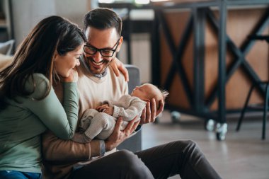 Gülümseyen anne ve baba yeni doğan kızlarını kucağında tutuyorlar. Aile ebeveynliği kavramını seviyorum.
