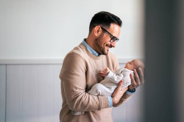 Yeni doğmuş bebeğini kucaklayan ve öpen bir babanın portresi. Erkek ebeveyn çocuğunu tutuyor. Otantik yaşam tarzı dokunaklı bir an. Bekar baba aile hayatı konsepti.