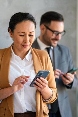 Ofisteki Orta yaşlı Asyalı iş kadını. Başarılı bir kadın cep telefonuyla mesaj atıyor ve çalışıyor. Gülümseyen iş kadını.