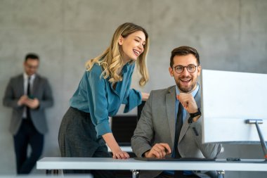 Ofiste yeni bir proje üzerinde çalışırken gülen iş adamları. Modern bir çalışma alanında çalışırken bilgisayar kullanan bir grup farklı iş adamı..