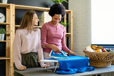 Mutlu evlatlık çocuk siyahi annelere ev işlerini ve ev işlerini birlikte yapmaları için yardım ediyor. Mutlu aile kavramı.