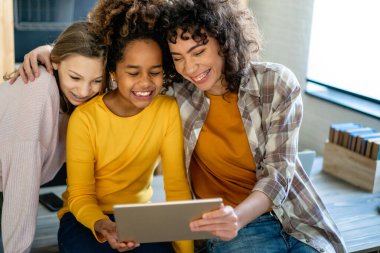 Modern aletleri ve dizüstü bilgisayarı olan bir grup genç evde birlikte ders çalışıp eğleniyorlar.