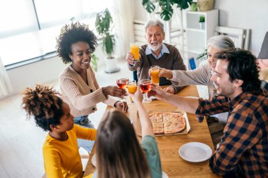 Karı, koca, çocuklar, büyükbaba ve büyükanneyle birlikte yemek yerken çok ırklı mutlu olun.