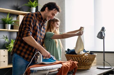 Mutlu bir baba ve kızı evde ev işleri yapıyor ve birlikte ütü yapıyor. İnsanların mutluluk kavramı.