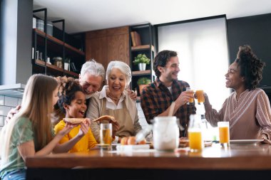 Karı, koca, çocuklar, büyükbaba ve büyükanneyle birlikte yemek yerken çok ırklı mutlu olun.
