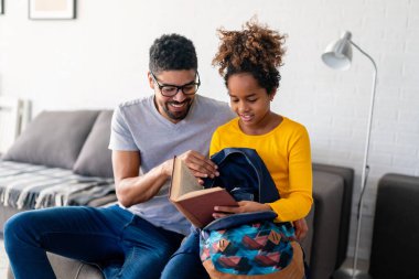 Siyah baba, kızının okul için bavulunu toplamasına yardım ediyor. Mutlu aile ve bekar ebeveynlik kavramı