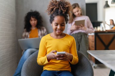 Bir grup genç kız arkadaş alet kullanıyor, konuşuyor ve birlikte gülümsüyorlar. İnsan teknolojisi kavramı.