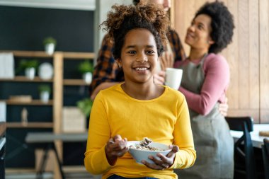 Mutfakta mısır gevreği yiyen mutlu siyah kız çocuğu..