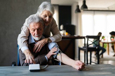 Yaşlı çift, kan basıncını ölçer. Ev sağlığı kontrolü kavramı, sağlık hizmetleri