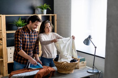 Mutlu genç çift evde ütü yapıyor.