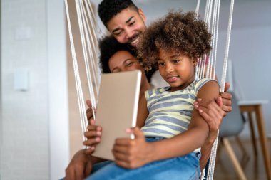 Mutlu Afro-Amerikan ailesi evde aletle eğleniyor. Siyah ebeveynler ve çocuklar dijital tablet kullanıyorlar
