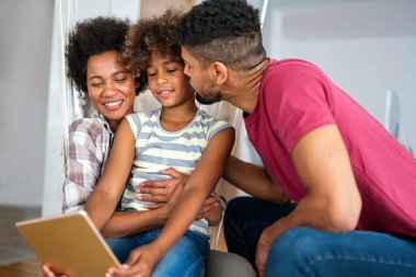 Aile tableti ve evde mutluluk, gelişme ve internet bağlantısı ile öğrenen çocuklar. Erkek, kadın ve kız birlikte kanepede eğitim, oyun ve internet uygulaması teknolojisiyle