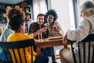 Multiethnic diverse extended family dining and toasting together with grandparents and children clipart