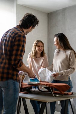 Mutlu çoklu etnik aile ev işlerini birlikte yapıyor, ütü yapıyor, evde birlikte ev işi yapıyor..