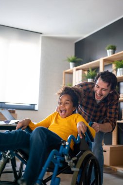 Tekerlekli sandalyede özürlü çocuklu, çok ırklı mutlu bir aile. Tek ebeveynlik