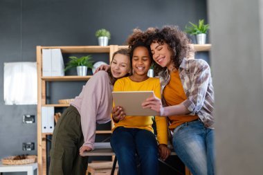 Çok ırklı öğrenci kızlar, dijital cihazlar kullanan kız kardeşler, birlikte eğlenmek ya da ders çalışmak..