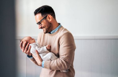 Yeni doğmuş bebeğini kucağında tutan genç babanın yakın plan portresi. Babalık yuvası, yalnız babalar günü konsepti ile birlikte yaşam tarzını sever.