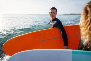 Gün batımında sörf yapan zinde bir çift. Sörfçü arkadaşlar okyanusun içinde eğleniyor. Ekstrem spor ve tatil konsepti