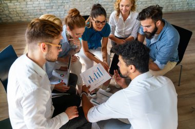 Çeşitli iş adamları tablolar ve grafiklerde mali raporu tartıştılar, iş ortakları ortak satış istatistiklerini analiz ederek grup toplantılarında anlaşma avantajları sundular