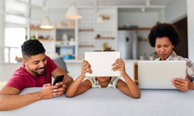 Teknolojik cihazlara takıntılı mutlu Afro-Amerikan genç ailesi dijital tablet, bilgisayar, akıllı telefonlar kullanıyor..