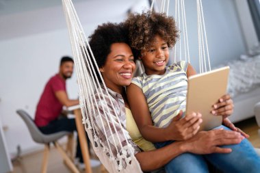 Mutlu Afro-Amerikan ailesi evde aletle eğleniyor. Siyah ebeveynler ve çocuklar dijital tablet kullanıyorlar