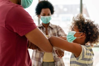 Ev karantinası sırasında maskeli genç Afro-Amerikan ailesi. Ailesi koronavirüs ve grip salgını sırasında maske takıyor. Virüs ve hastalık koruması, COVID