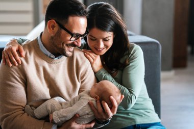 Gülümseyen anne ve baba yeni doğan kızlarını kucağında tutuyorlar. Aile ebeveynliği kavramını seviyorum.