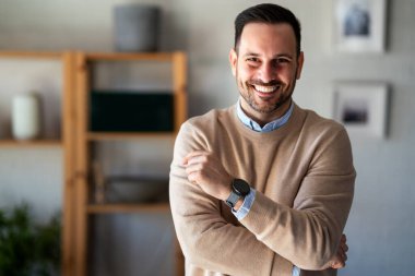 Yapılan işten memnun. Ofisinde çalışırken dizüstü bilgisayarda çalışan mutlu genç adam.