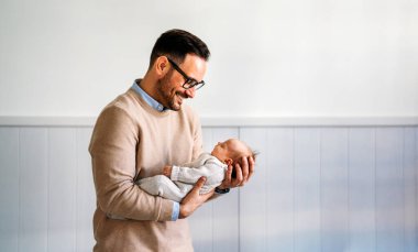 Yeni doğmuş bebeğini kucağında tutan genç babanın yakın plan portresi. Babalık yuvası, yalnız babalar günü konsepti ile birlikte yaşam tarzını sever.