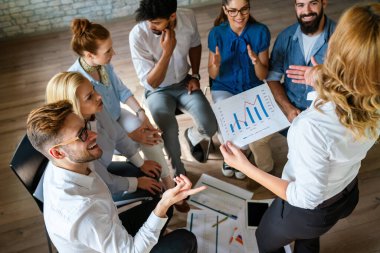 Bir grup çok ırklı iş adamı ofis masasında mali raporları analiz ediyor ve ofiste bir takım olarak çalışıyorlar.