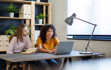 Kütüphanede ders çalışan, birlikte vakit geçiren çok ırklı genç arkadaşların kutlu olsun. Gençlik eğitimi kavramı.