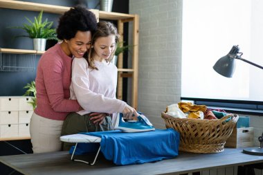 Mutlu evlatlık çocuk siyahi annelere ev işlerini ve ev işlerini birlikte yapmaları için yardım ediyor. Mutlu aile kavramı.