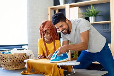 Mutlu siyah çocuk, babaya ev işlerinde ve ev işlerinde yardım ediyor. Mutlu aile kavramı.