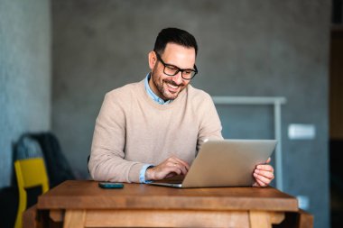 Ofiste dizüstü bilgisayarla çalışan gülümseyen bir iş adamı. Bilgisayarda uzaktan eğitim, sanal eğitim kullanan genç öğrenci ya da uzaktan öğretmen.