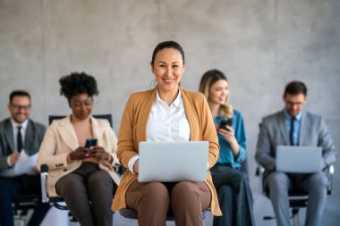 Ofiste yeni bir proje üzerinde çalışırken gülen iş adamları. Modern bir çalışma alanında çalışırken bilgisayar kullanan bir grup farklı iş adamı..