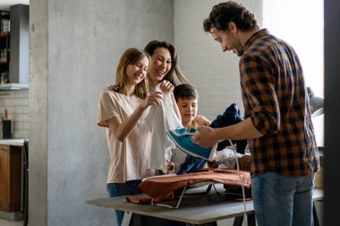 Mutlu çoklu etnik aile ev işlerini birlikte yapıyor, ütü yapıyor, evde birlikte ev işi yapıyor..