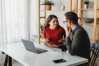 Business professionals collaborating on a project in a modern office. The team of coworkers, consisting of men and women, are engaged in a lively discussion, technology and sharing ideas. clipart