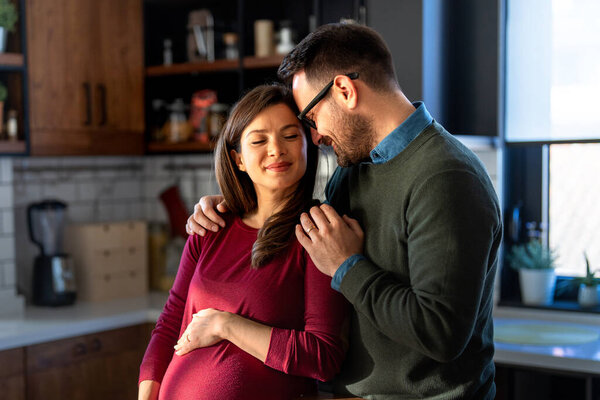 Concept of love, tenderness, relationship and new family. A man in love hugs his pregnant wife, they are waiting together for the babys arrival
