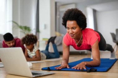 Spor yoga videoları. Evde spor yapma dersi online olarak canlı yayınlanıyor. Mutlu Afro-Amerikan kadın egzersizleri.