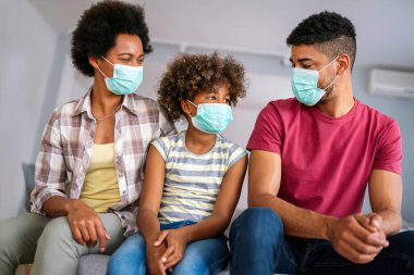 Ev karantinası sırasında maskeli genç Afro-Amerikan ailesi. Ailesi koronavirüs ve grip salgını sırasında maske takıyor. Virüs ve hastalık koruması, COVID