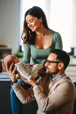 Mutlu bir genç adam ve kadın holding yeni doğan şirin bebek portre beyaz unisex kılığına girmiş. Beyaz gülümseyen baba ve anne kucaklayan şefkatle çok güzel yeni doğan çocuk. Mutlu aile kavramı