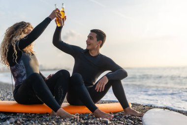 Gün batımında sörf yapan zinde bir çift. Sörfçü arkadaşlar okyanusun içinde eğleniyor. Ekstrem spor ve tatil konsepti