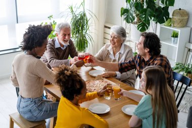 Multiethnic diverse extended family dining and toasting together with grandparents and children clipart