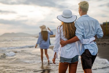 Genç bir çift gülümseyerek denizde yürüyor ve yaz tatilinin tadını çıkarıyor, birlikte seyahat ediyorlar. Yeni tatiller ve çiftler konsepti.
